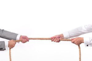 Tug war, two businessman pulling a rope in opposite directions isolated on white background